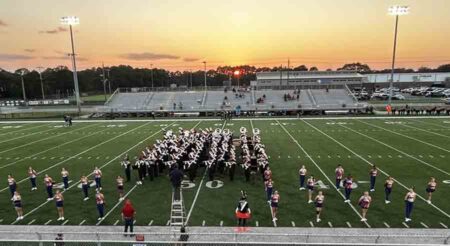 The Fort Walton Beach High School Viking Band on a football field at twilight.