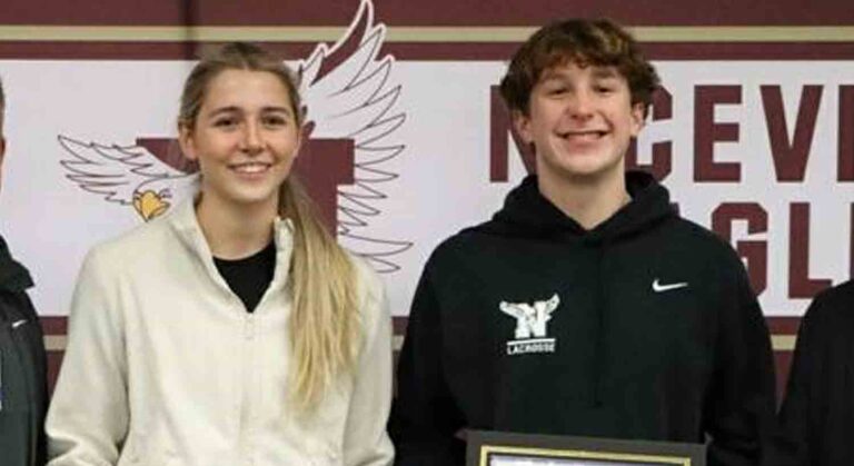 Niceville High School seniors Maxwell Diehl and Sophie Broutin stand in front of a school banner.