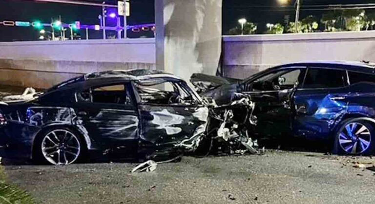 A crash scene in Destin, Florida, showing a black Dodge Charger with significant damage alongside another damaged vehicle. The area is illuminated by streetlights.