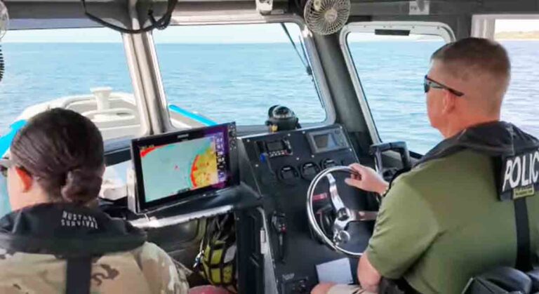 Law enforcement officers patrol restricted Eglin Air Force Base waterways in a police-marked boat, monitoring security threats.