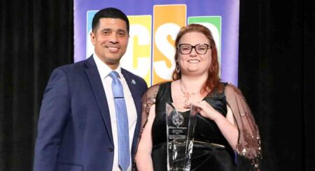 Okaloosa County Superintendent Marcus Chambers poses with Teacher of the Year Katrina Brownsburger, who is holding her award at the 2025 OCSD Teacher of the Year banquet.