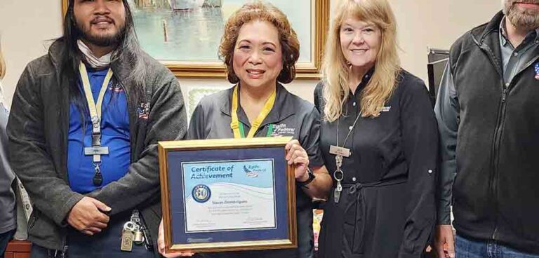 Susan Dombrigues holds a framed Certificate of Achievement while celebrating her 30-year service milestone at Eglin Federal Credit Union, joined by colleagues.