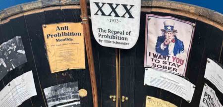 Close-up image of a history project on Prohibition displayed inside a wooden barrel, featuring historical documents, images, and a glass jar labeled "XXX - 1933."