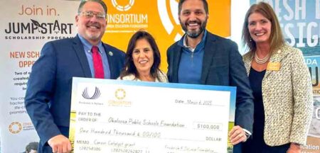 Four individuals stand together holding an oversized check for $100,000 made out to the Okaloosa Public Schools Foundation, awarded through the Career Catalyst grant initiative.