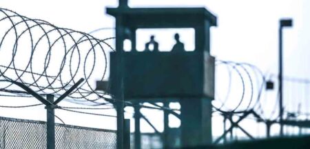 Guard tower and barbed wire fence at a high-security prison.