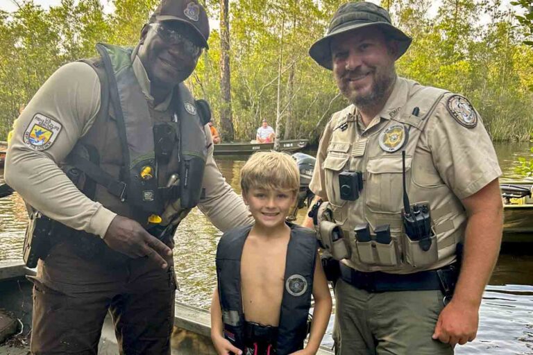 Smiling young boy with two uniformed rescue personnel after water search