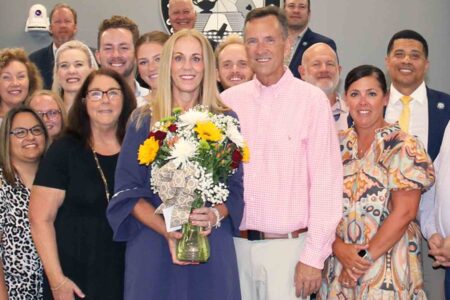 Holly Tew holds a bouquet of flowers and poses with family and colleagues.