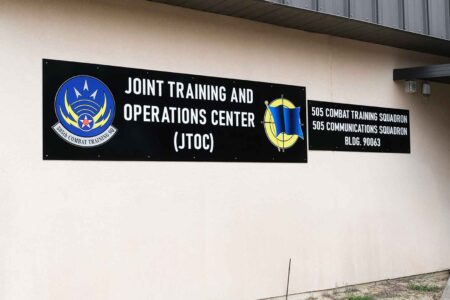 photo of a building with brown signs that have wording “Joint Training and Operations Center (JTOC) and 505th Combat Training Squadron and 505th Communications Squadron”