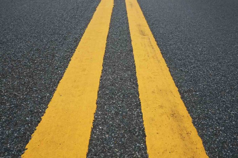 Close-up of double yellow lane stripes on an asphalt road surface.