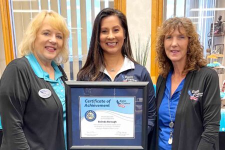 Three Eglin Federal Credit Union employees stand together, holding a framed certificate recognizing 30 years of service