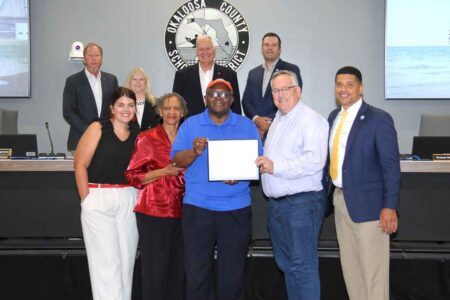 Sanford Hayes holds a certificate surrounded by school board members and supporters.