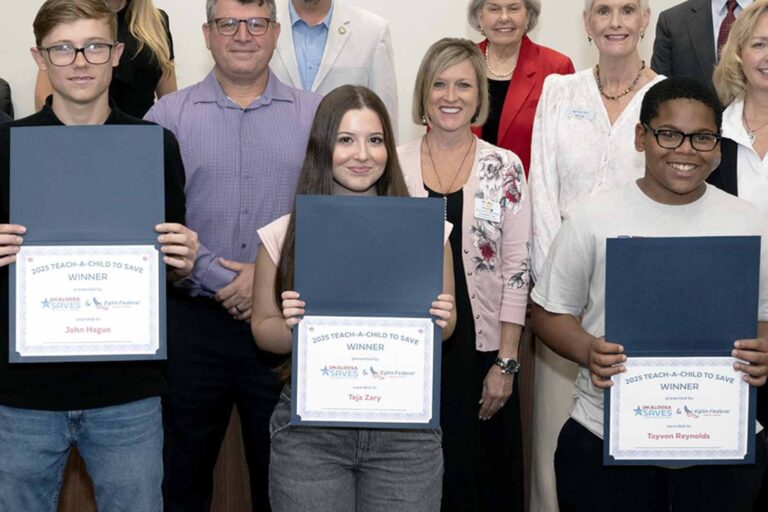 Three student winners hold certificates during the 2025 Teach Children to Save campaign recognition event in Okaloosa County.