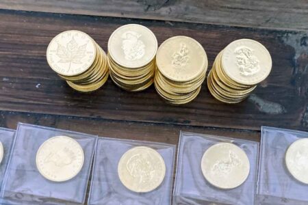 Stacks of gold coins and bullion displayed on a wooden surface