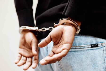 Close-up of a person in handcuffs with hands behind their back