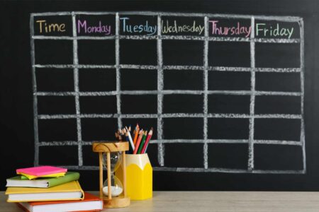Blank school week calendar on chalkboard with books and pencils