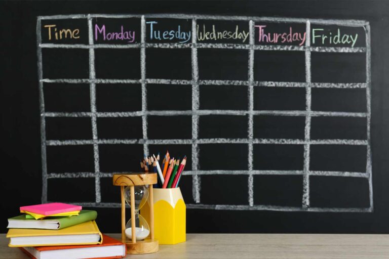 Blank school week calendar on chalkboard with books and pencils