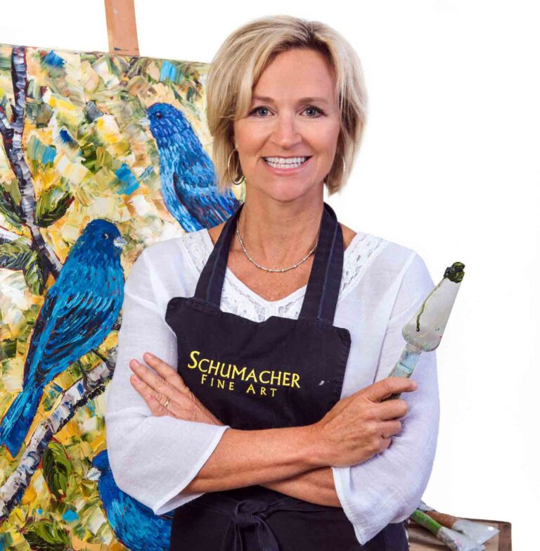 Kathy Schumacher standing in front of her artwork while holding a palette knife.