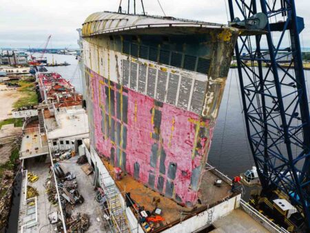 A close-up of the SS United States funnel being lifted by crane from the deck of the ship.