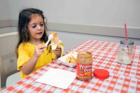 A child spreads peanut butter on a banana during the Peanut Butter Challenge.