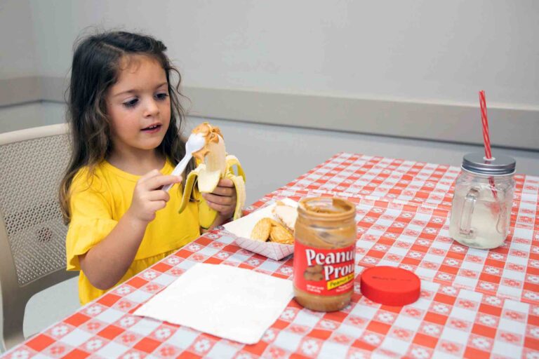 A child spreads peanut butter on a banana during the Peanut Butter Challenge.