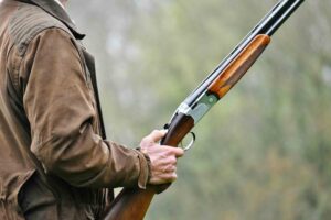 A hunter holding a shotgun outdoors in preparation for recreational hunting.