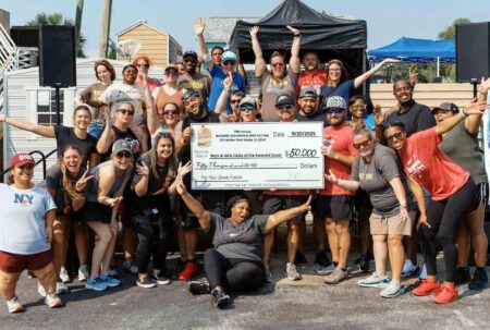 Group of smiling festival organizers and volunteers holding a $50,000 donation check to the Boys & Girls Clubs of the Emerald Coast.