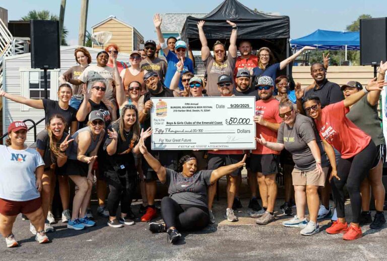 Group of smiling festival organizers and volunteers holding a $50,000 donation check to the Boys & Girls Clubs of the Emerald Coast.