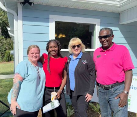 Eglin Federal Credit Union and Habitat for Humanity representatives stand with two new Crestview homeowners during a home dedication ceremony.