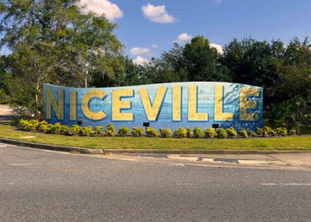 The Niceville mural featuring large yellow letters spelling “Niceville” on a blue background along John Sims Parkway.
