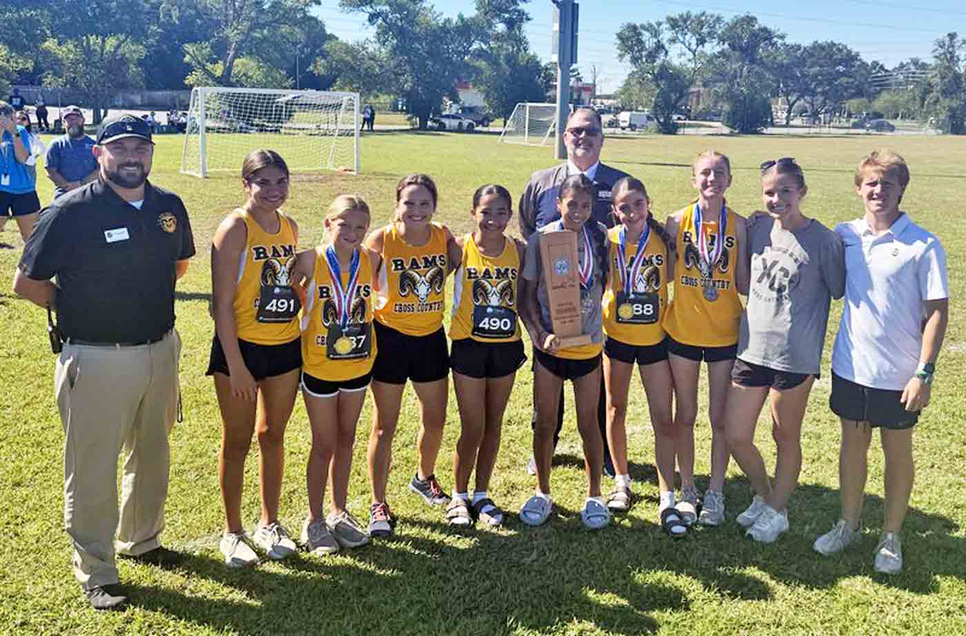 Ruckel Middle School girls cross country team stands with coaches and administrators at the Twin Oaks Complex after winning the 2025 county championship.