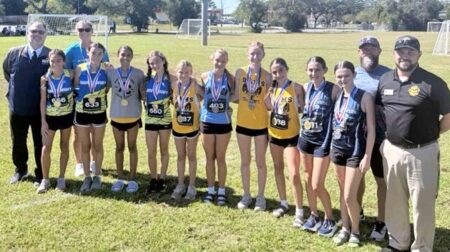 Top 10 girls from the 2025 Okaloosa County Middle School Athletic Conference Cross Country Championship stand together wearing medals at the Twin Oaks Complex in Niceville.