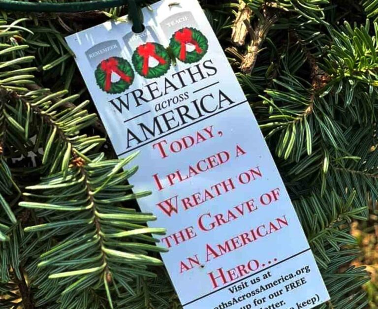 A Wreaths Across America tag tied to a holiday wreath branch.