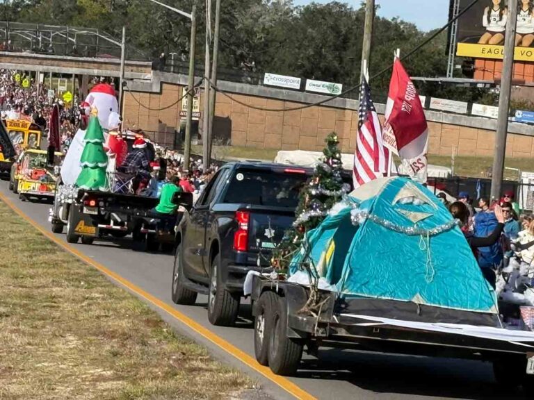 Floats decorated with Christmas trees, flags, and holiday scenes travel down John Sims Parkway during the Niceville Christmas Parade.
