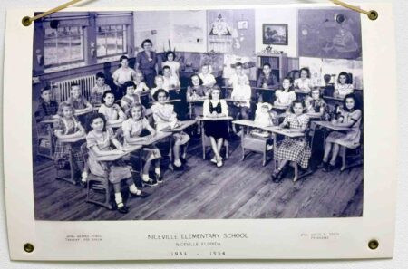 Historic 1953–1954 Niceville Elementary School classroom photo showing students seated at wooden desks with their teacher standing at the back.