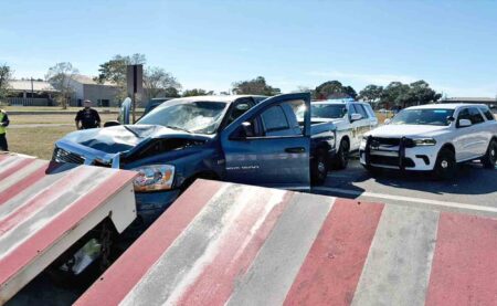 Damaged pickup truck after striking red and white barrier near an Eglin Air Force Base checkpoint, with OCSO vehicles behind it.
