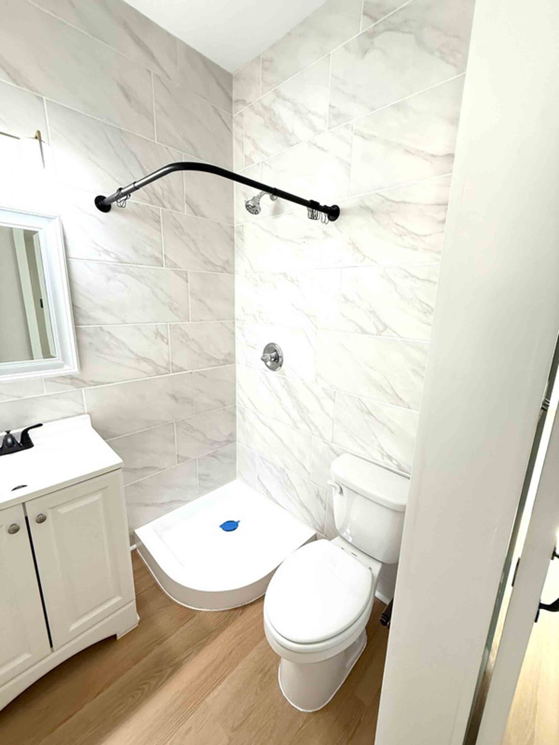 Bathroom inside an Okaloosa Technical College student-built tiny home, featuring a tiled shower area, white vanity, and toilet.