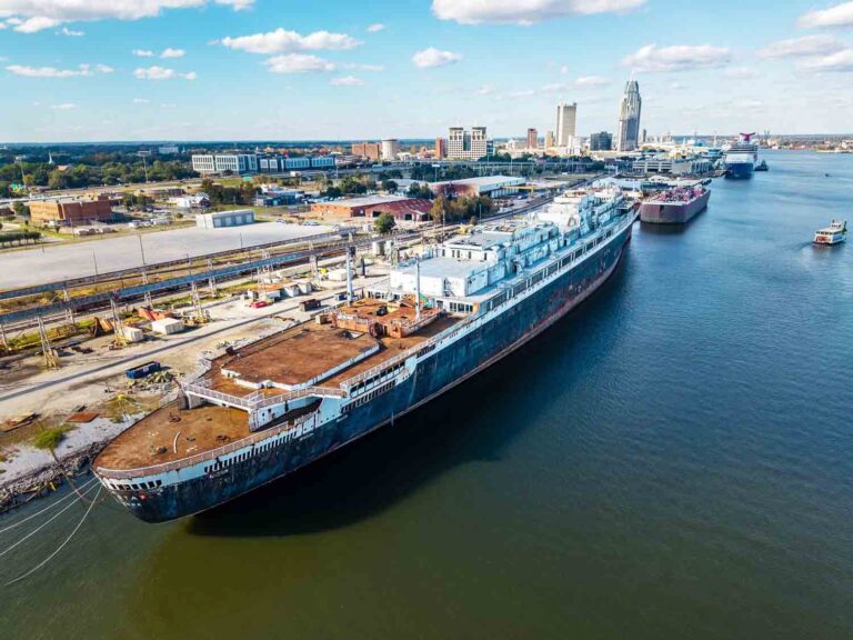 The SS United States docked in Mobile, Alabama, with the city skyline in the background.