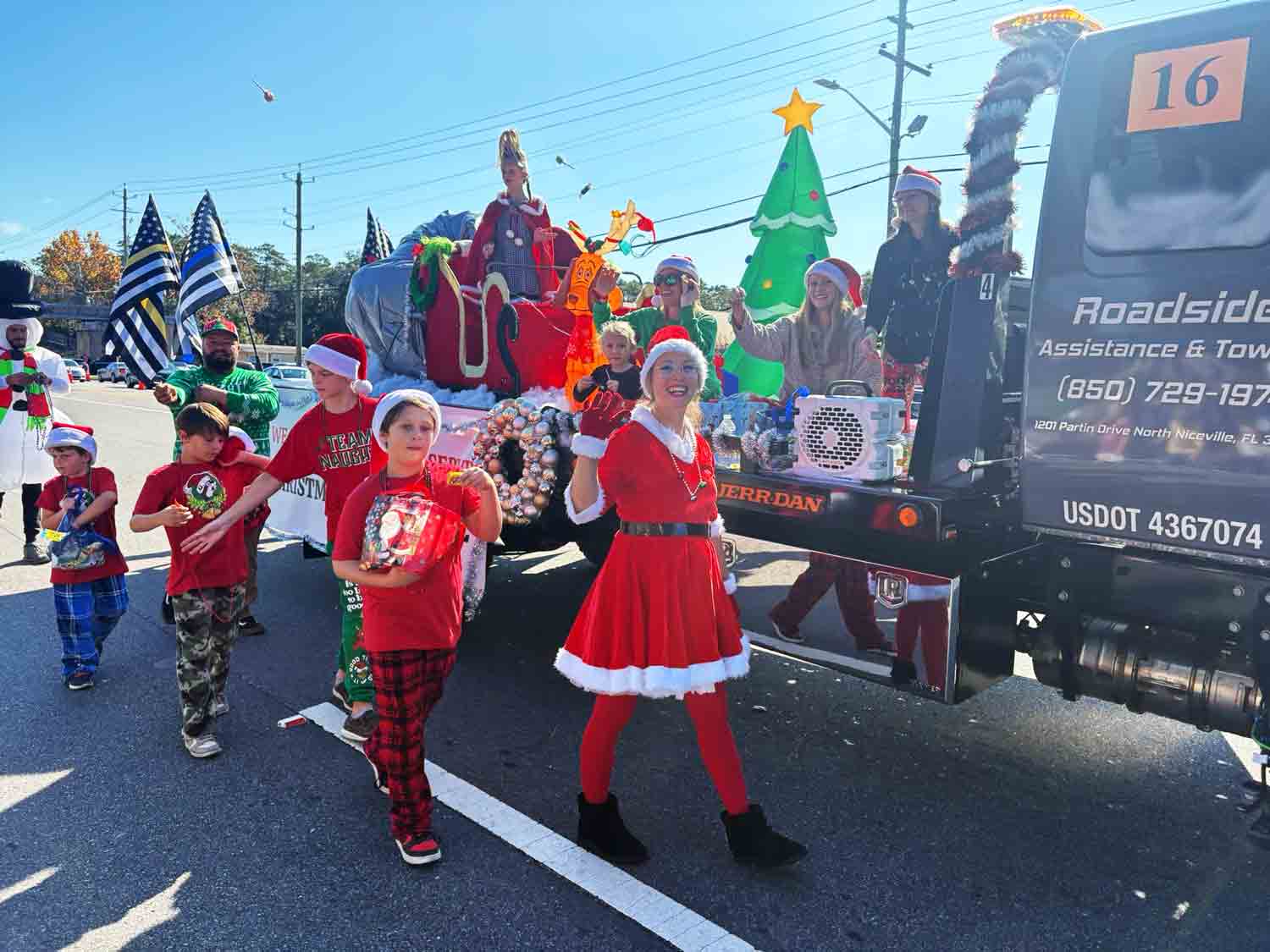 Parade participants dressed in holiday costumes walk alongside a festive float during the Niceville Christmas Parade.
