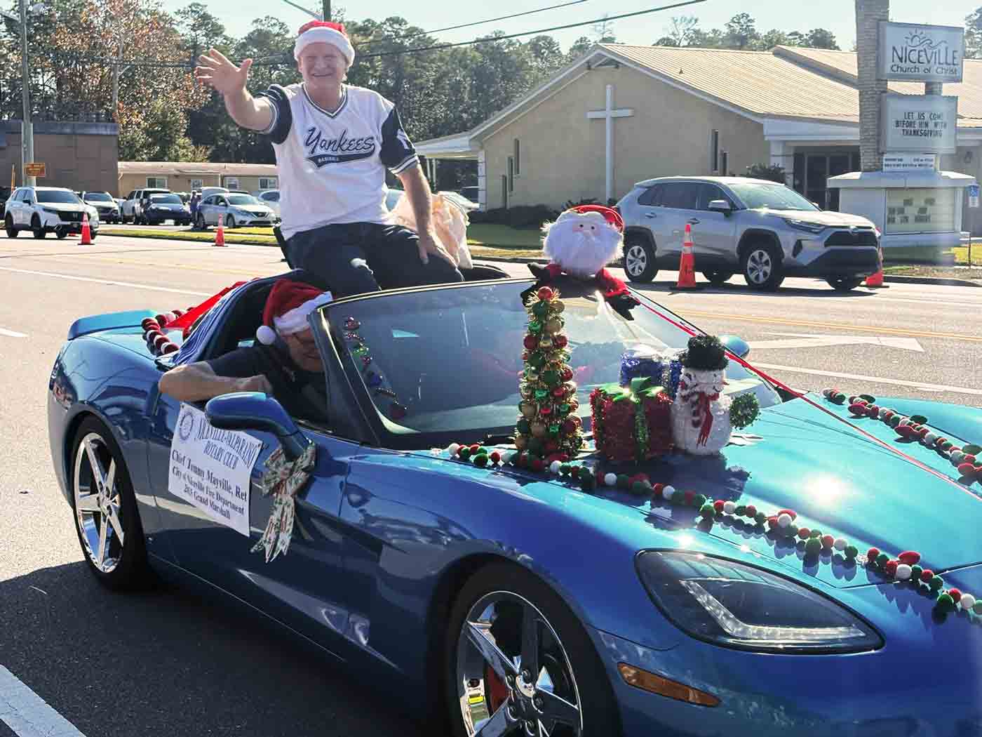 Grand Marshal Tommy Mayville waves from a decorated car during the Niceville Christmas Parade.