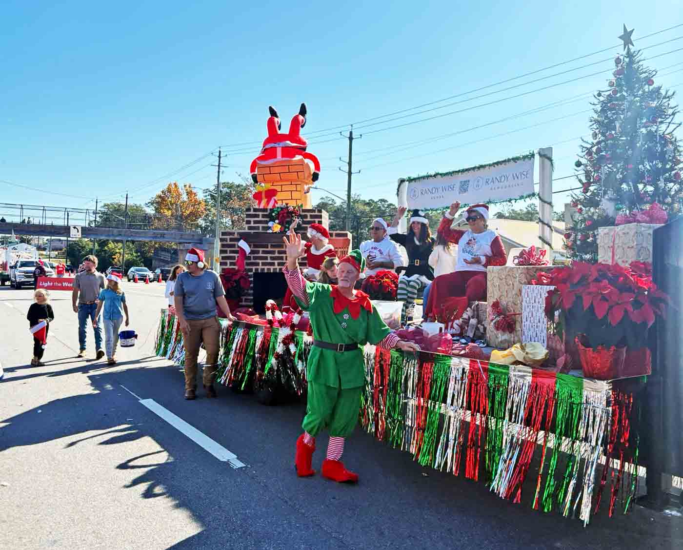A holiday parade float featuring elves and Christmas decorations travels along John Sims Parkway during the Niceville Christmas Parade.