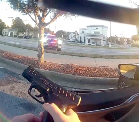 Teen charged after BB gun recovered in Walton County road rage case A deputy points a black BB gun toward a stopped vehicle with emergency lights activated across a parking lot.