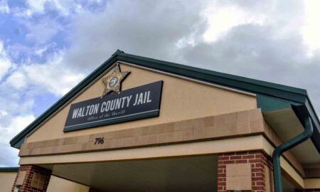 The front entrance of the Walton County Jail building under a cloudy sky.