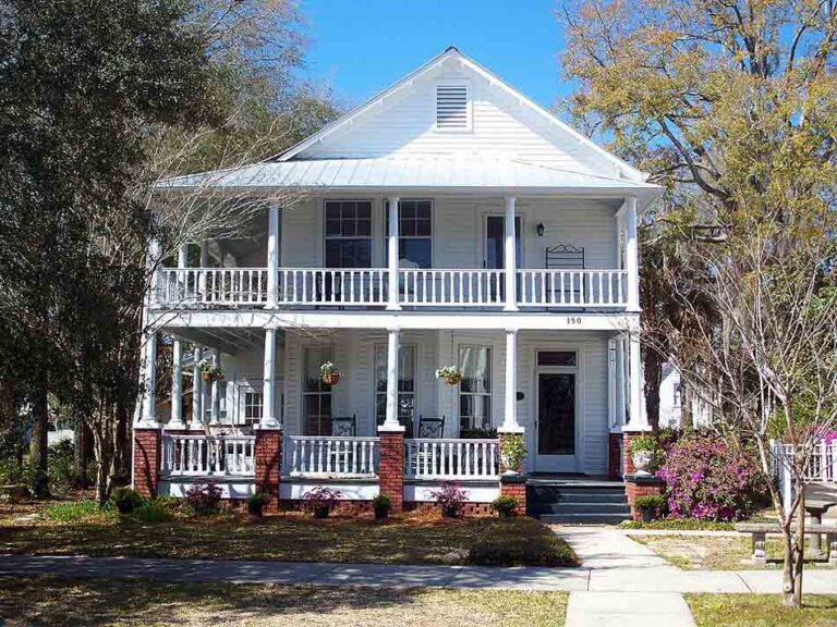 A historic two-story white home with double porches and brick columns in DeFuniak Springs.