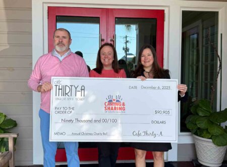 Representatives from Café Thirty-A and Caring and Sharing of South Walton hold a ceremonial check for $90,905 outside the restaurant in Seagrove Beach.