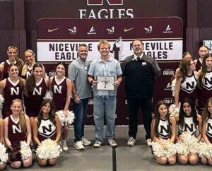 Niceville High School senior Harper Campbell holds his Taylor Haugen Trophy certificate while standing with school administrators and cheerleaders.