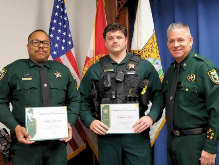 Two Okaloosa County Sheriff’s Office deputies stand with Sheriff Eric Aden during a commendation award presentation.