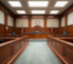 Mary Esther man pleads guilty to fentanyl, firearm charges Blurred interior view of a courtroom with judge’s bench, seating areas, and American flags.