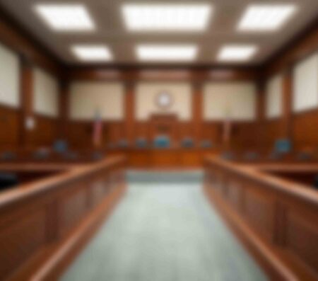 Mary Esther man pleads guilty to fentanyl, firearm charges Blurred interior view of a courtroom with judge’s bench, seating areas, and American flags.