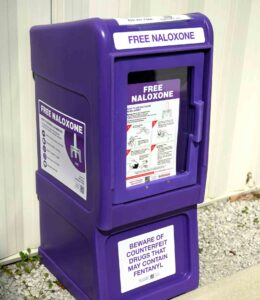 Purple outdoor Narcan distribution box labeled “Free Naloxone” outside Niceville Fire Station.