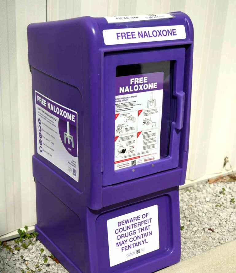 Purple outdoor Narcan distribution box labeled “Free Naloxone” outside Niceville Fire Station.